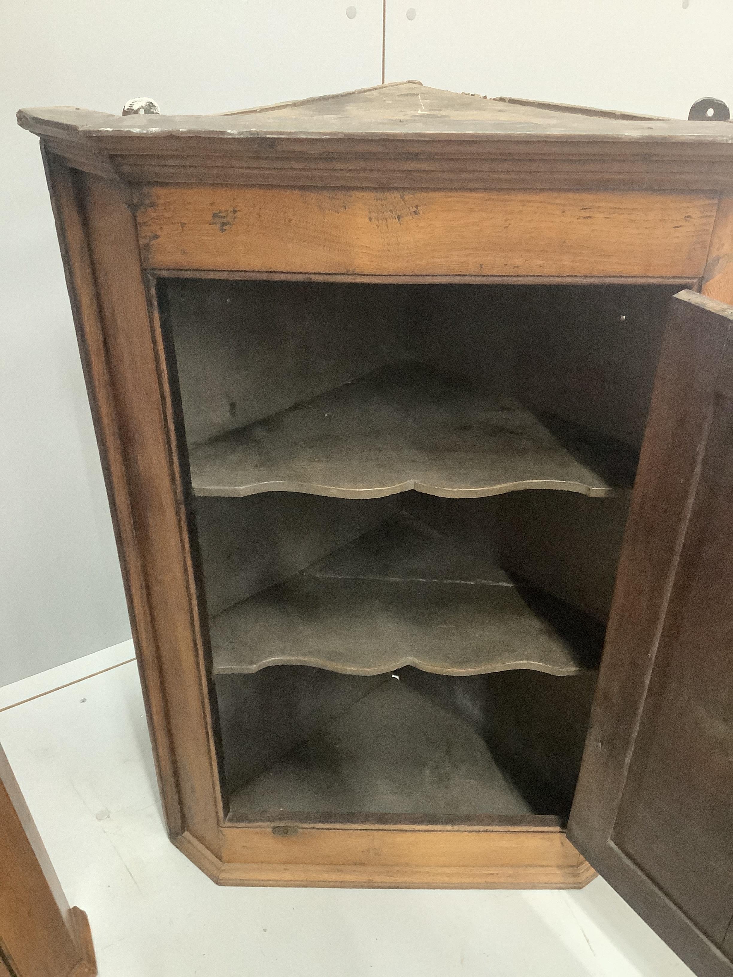 A George III inlaid oak hanging corner cupboard, width 87cm and a similar plainer example, width 62cm